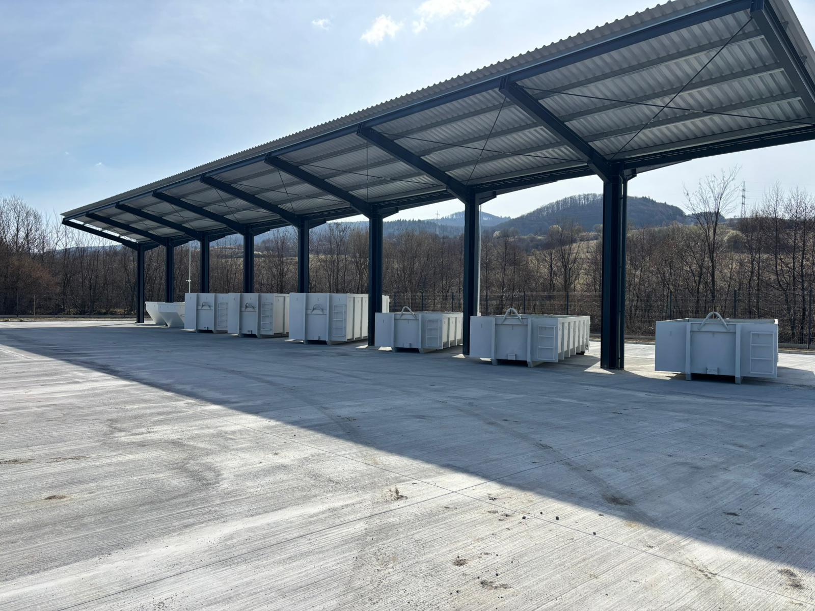 Vedere de ansamblu a copertinei metalice și a containerelor sub aceasta, în lumina dimineții